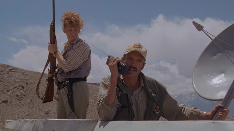 Reba McEntire as Heather and Michael Gross as Burt on their roof with guns in Tremors