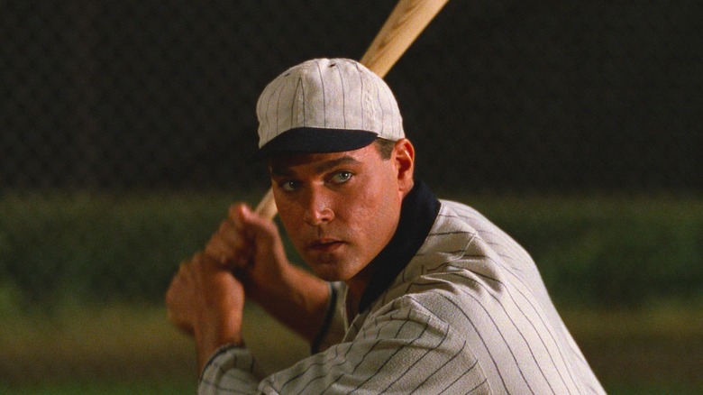 ஃபீல்ட் ஆஃப் ட்ரீம்ஸில் மர மட்டையை பிடித்தபடி பேஸ்பால் சீருடையில் ஷூ இல்லாத ஜோ ஜாக்சனாக ரே லியோட்டா