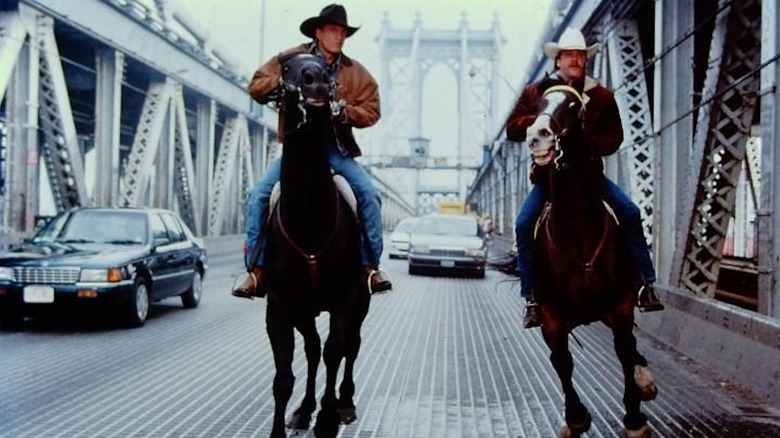 Woody Harrelson as Pepper Lewis and Kiefer Sutherland as Sonny Gilstrap ride horses on a Manhattan bridge in The Cowboy Way