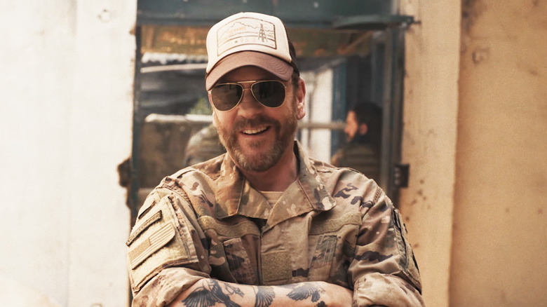 Kiefer Sutherland's Capt. Jordan Wright stands smiling while wearing shades in Brothers Under Fire
