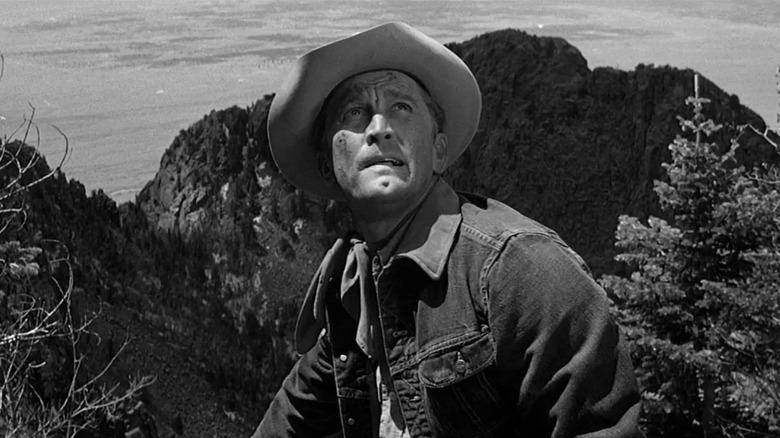 Jack Burns from Lonely Are the Brave, in front of a massive New Mexico ridge, looking worriedly at the sky
