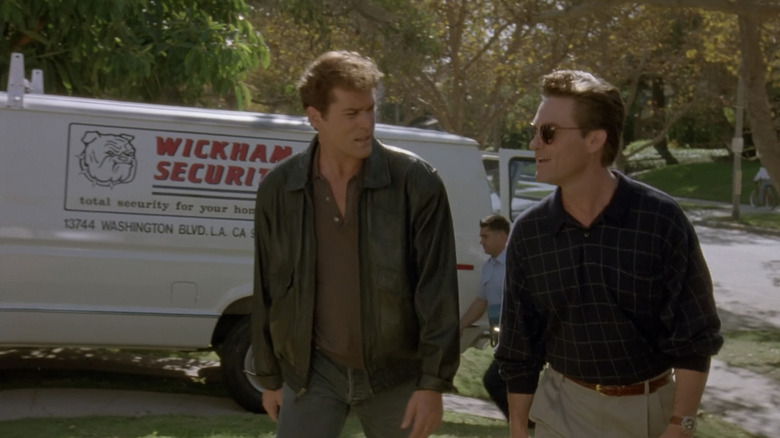 Ray Liotta's agent Pete Davis loopt naast Michael Carr van Kurt Russell in een straat in een buitenwijk in Unlawful Entry