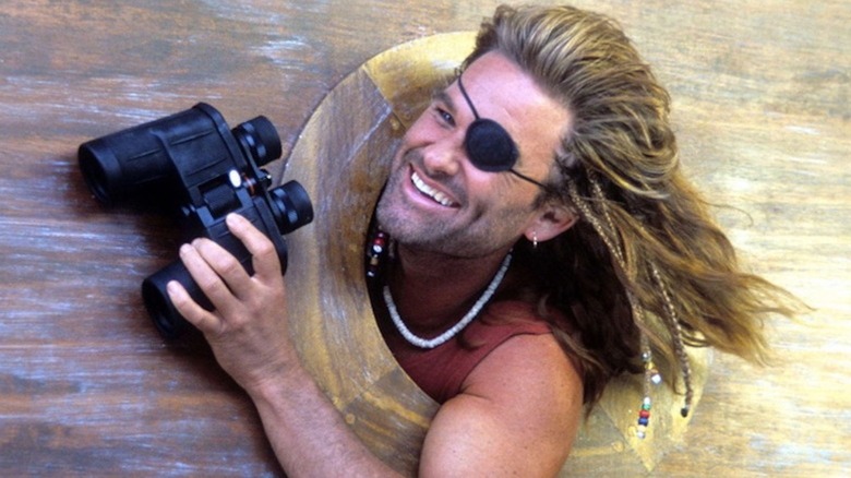 Kurt Russell pokes through a porthole with a pair of binoculars as the rascally Captain Ron