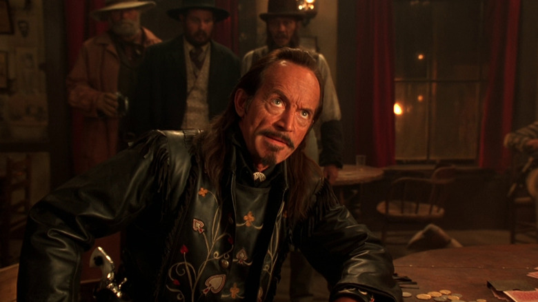 Ace Hanlon sitting in a saloon in The Quick and the Dead