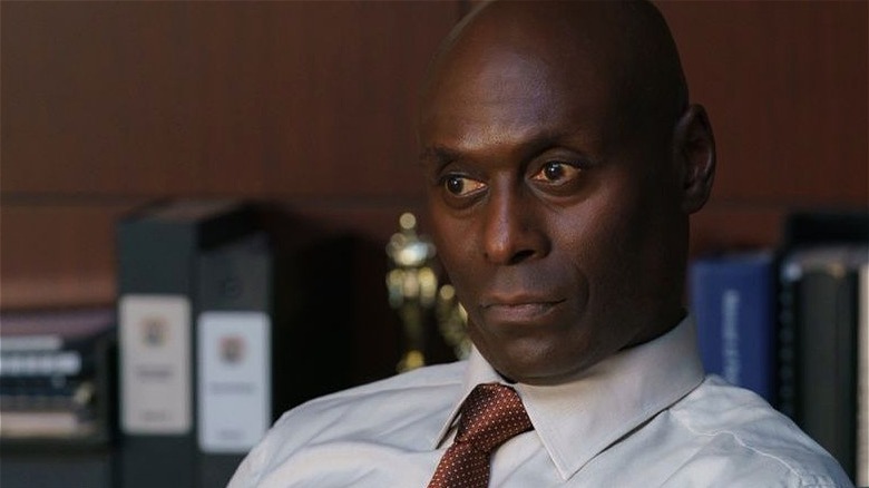 Irving sitting at desk in tie looking deep in thought on Bosch