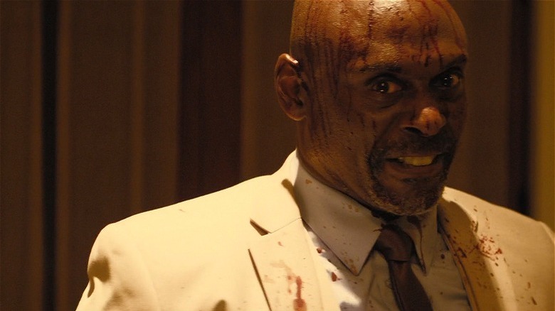 Milo with suit and blood on his face looking deranged in Monster Party