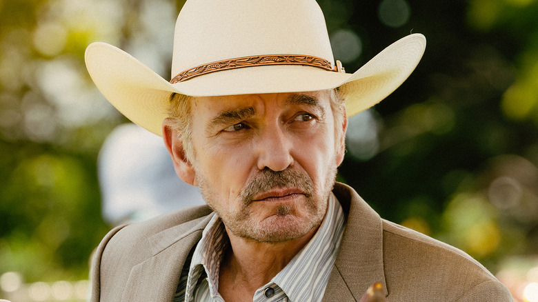 Billy Bob Thornton's Tommy Norris sits at a table outside during a party in Landman