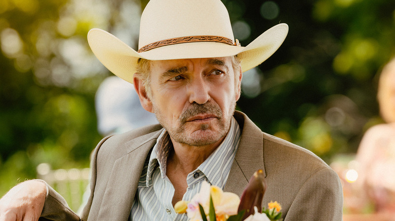 Billy Bob Thornton's Tommy Norris sits at a table outside during a party in Landman