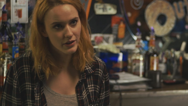 Rachel Brosnahan's Jamie looks through the frame as she stands at a bar in Boomtown