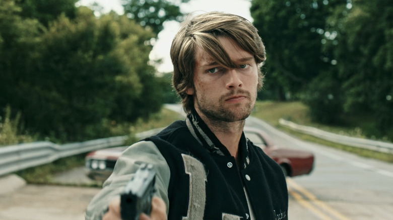 గో నార్త్‌లోని రోడ్డుపై నిలబడి పాట్రిక్ స్క్వార్జెనెగర్ యొక్క కాలేబ్ తుపాకీని పట్టుకున్నాడు