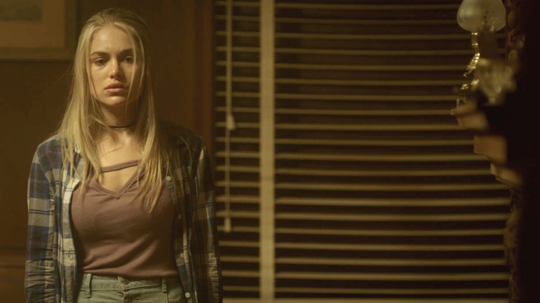 Michelle Randolph's Rachel standas looking worried in a dimly lit room in House of the Witch