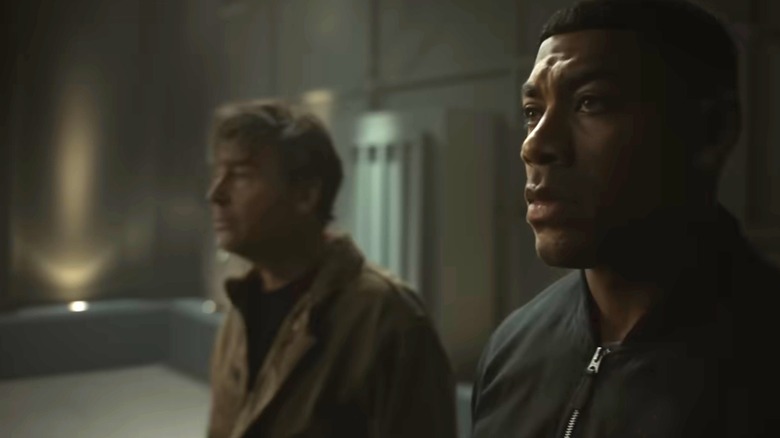 Aaron Pierre as John Stewart standing next to Kyle Chandler as Hal Jordan in a darkened room in Lanterns