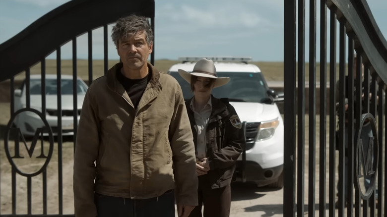 Kyle Chandler as Hal Jordan standing by an iron gate in front of Kelly Macdonald as Sheriff Kerry Kane in Lanterns