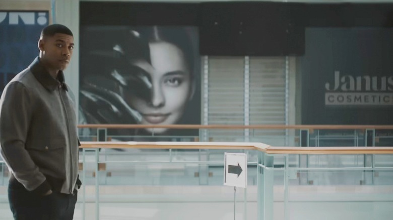 Aaron Pierre's John Stewart stands in front of a sign for Janus Cosmetics in Lanterns