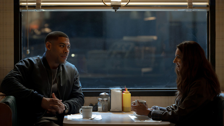 Aaron Pierre's John Stewart sits opposite Poorna Jagannathan's Zoe Macon in a diner in Lanterns.jpg