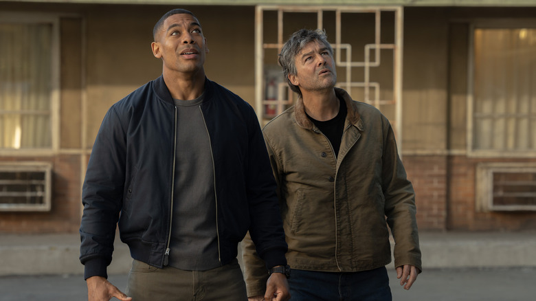 Kyle Chandler's Hal Jordan and Aaron Pierre's John Stewart stand side by side looking upwards outside a motel in Lanterns