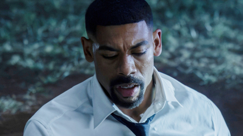 Aaron Pierre's John Stewart wearing a white shirt and holding a Green Lantern ring at night in Lanterns