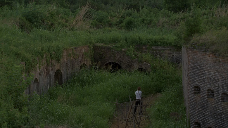 Matthew McConaughey's Rustin Cohle stands in the center of stone ruins in True Detective