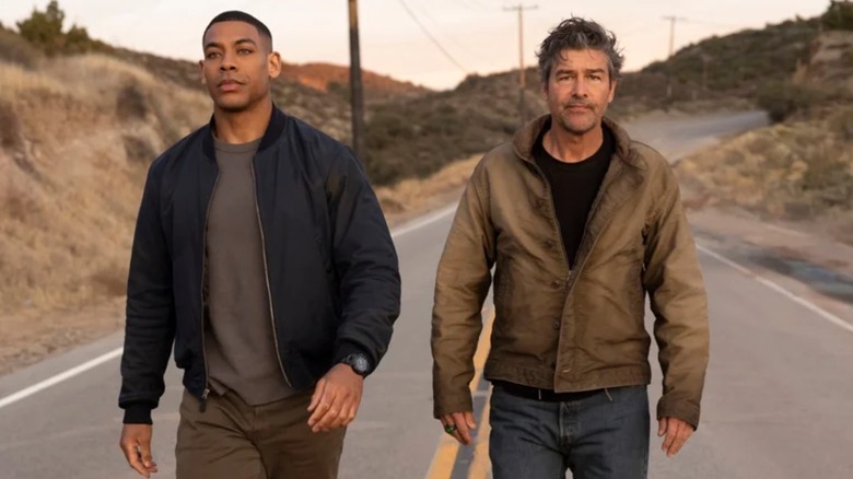 Aaron Pierre and Kyle Chandler as John Stewart and Hal Stewart walking down a highway in Lanterns