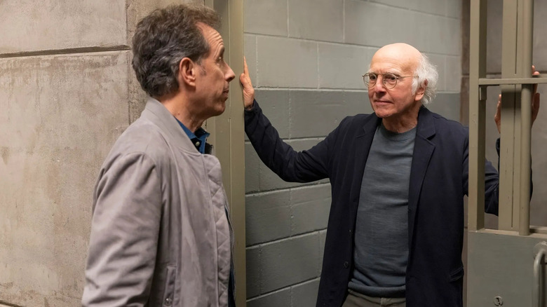 Jerry Seinfeld and Larry David stand at the threshold of a jail cell in Curb Your Enthusiasm