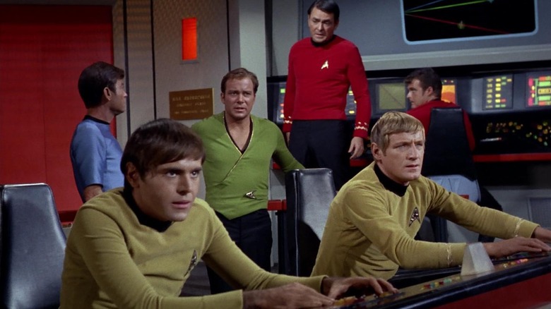 Chekov, Kirk, McCoy, Scotty, and two other officers on the bridge of the Enterprise on Star Trek