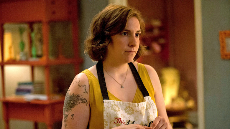 Hannah staring at someone wearing an apron and a yellow shirt on Girls