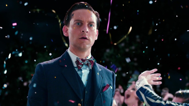 Tobey Maguire's Nick Carraway looks concerned as he stands outside during a fireworks display in The Great Gatsby