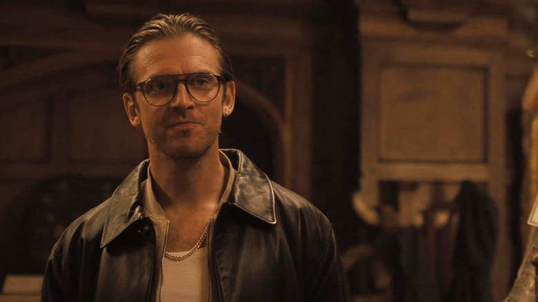 Dan Stevens as Frank smiling while wearing glasses in Abigail (2024)