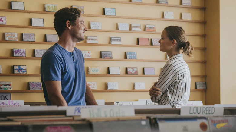 Lewis Pullman and Clara Rugaard as Laura and Harrison talking at a counter in Press Play