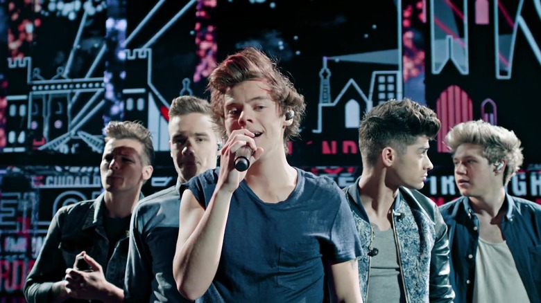 one boy singing with a microphone in front of four other boys in a pyramid shape