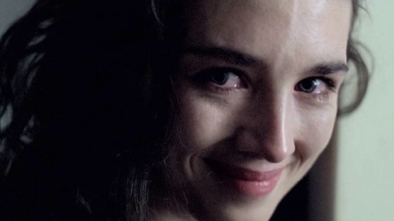 a woman crying and smiling menacingly at someone just off-camera