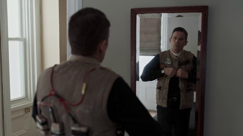 a man fastening an explosive vest onto himself in the mirror