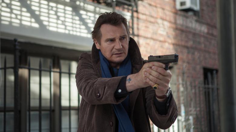 Liam Neeson as Matt Scudder holding a pistol in A Walk Among the Tombstones