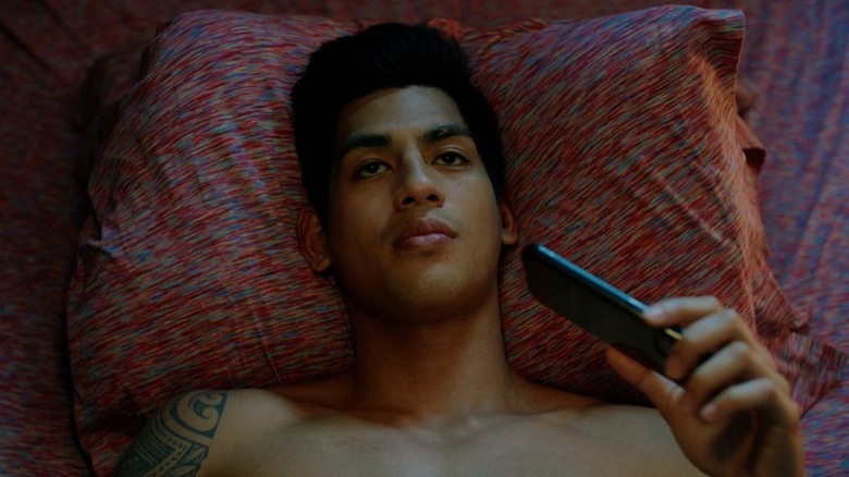 Kaipo Dudoit clutches a phone on his bed as Pili in My Partner