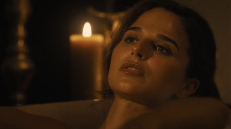 Stephanie Nur's Aaliyah Amrohi is seen in closeup as she lays in a bath surrounded by candles in Lioness