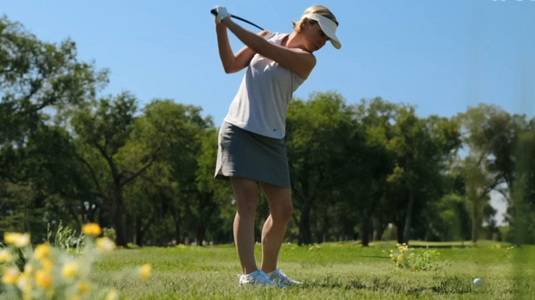 Rhea Seehorn as Carol Sturka winding up for a swing during a game of golf in Pluribus