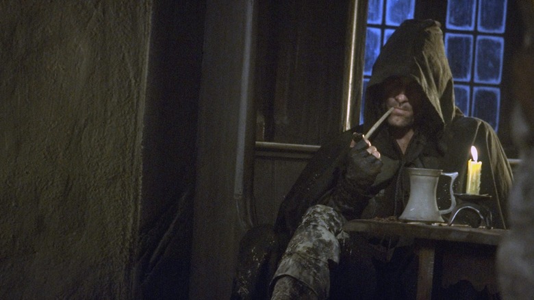 Aragorn as a hooded Ranger sitting in the Prancing Pony