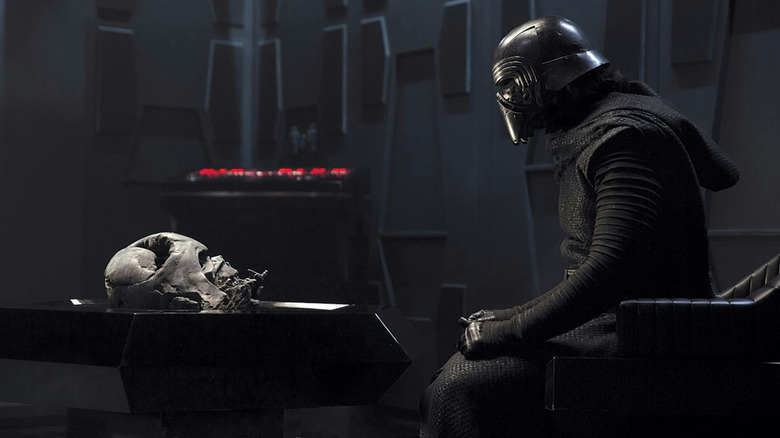Adam Driver als Kylo Ren zittend in een stoel tegenover de gesmolten helm van Darth Vader in Star Wars: The Force Awakens