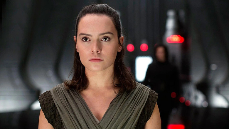 Daisy Ridley als Rey staat in een troonzaal met Adam Driver als Kylo Ren onscherp achter haar in Star Wars: The Last Jedi