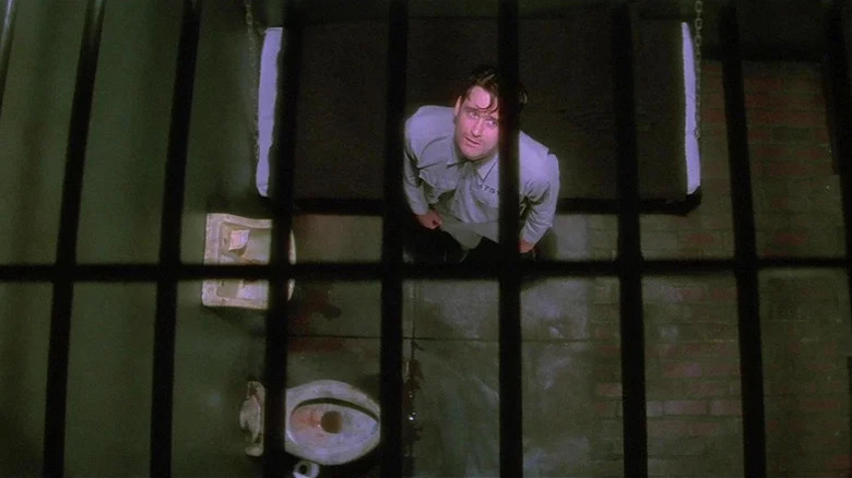 A bird's eye view of a haggard Fred, in a prison cell, from Lost Highway. There are bars on the ceiling.