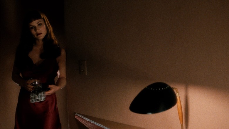 Renee, in a dark room, wearing a red dress and holding a drink, a moody shot from Lost Highway.
