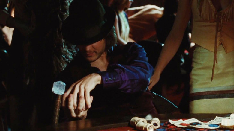 Taylor Kitsch as Gambit wearing a hat and sitting at a table gambling in X-Men Origins: Wolverine