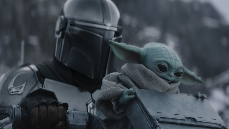 Mando and Grogu riding on a walking in the snow in The Mandalorian and Grogu