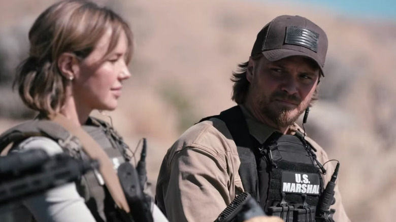 Arielle Kebbel as Belle and Luke Grimes as Kayce Dutton in U.S. Marshal vests on the TV series Marshals