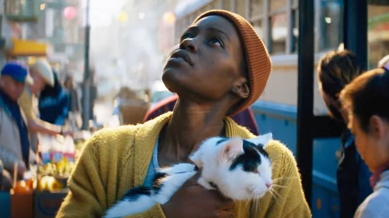 Sam holding her cat Frodo looking up at the sky in A Quiet Place: Day One