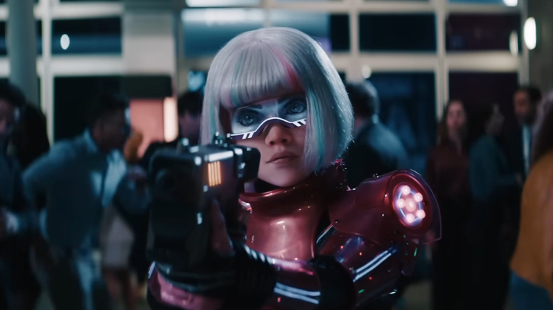 M3Gan holds a rifle in the pink robot suit in M3GAN 2.0