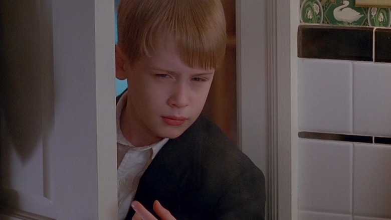 Macaulay Culkin's Kevin McCallister leans through a doorway looking suspicious in Home Alone 2: Lost in New York