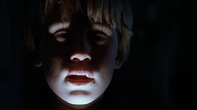 Macaulay Culkin's Henry Evans is illuminated by a flashlight held below his face in The Good Son