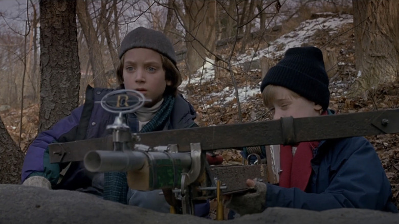 Elijah Wood's Mark Evans sits beside Macaulay Culkin's Henry Evans as he aims a makeshift crossbow in The Good Son
