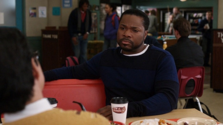 Andre Bennett sitting at a table with a coffee in Community